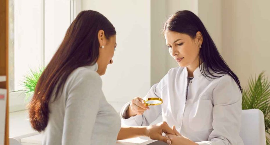 Female dermatologist examining skin of woman patient with magnifying glass. General practitioner doing skin examination in dermatology clinic. Professional doctor checking benign moles on arm
