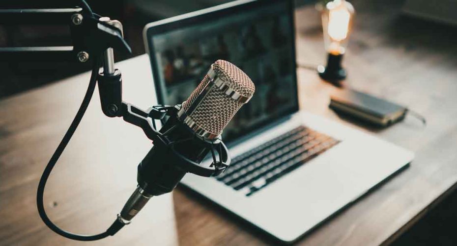 Home studio podcast interior. Microphone, laptop and on air lamp on the table, close-up