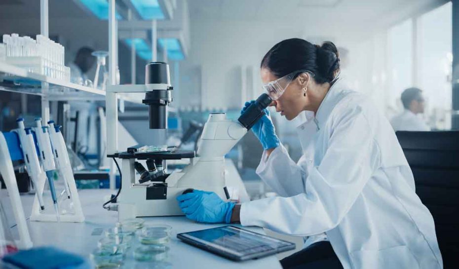 Medical Development Laboratory: Caucasian Female Scientist Looking Under Microscope, Analyzes Petri Dish Sample. Specialists Working on Medicine, Biotechnology Research in Advanced Pharma Lab